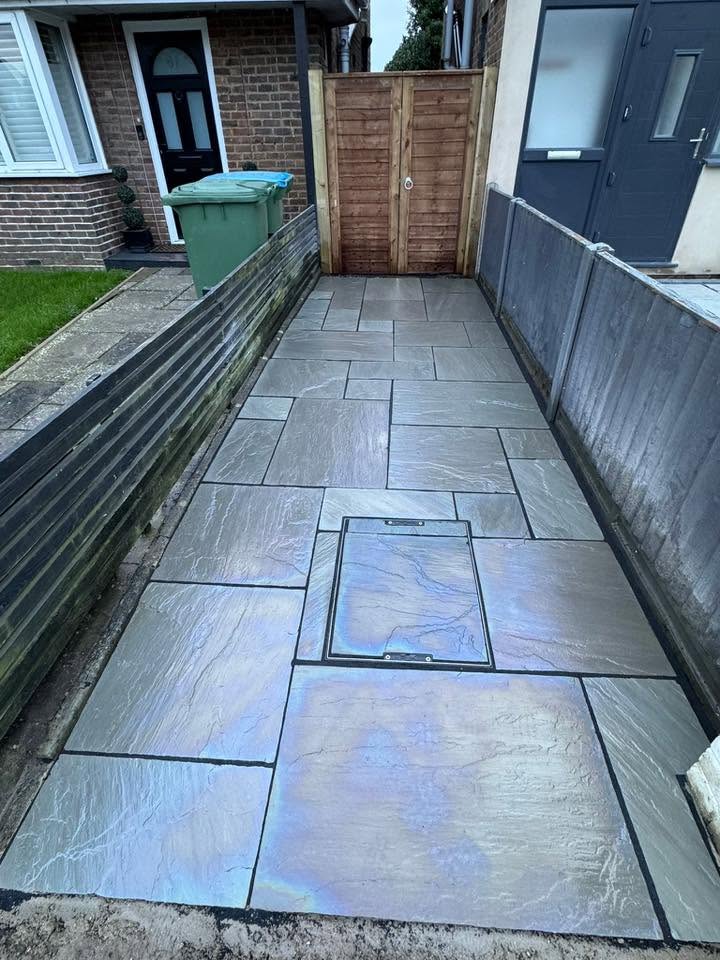 Grey sandstone side path with recessed manhole cover and new timber fence by A Baker Construction West Sussex