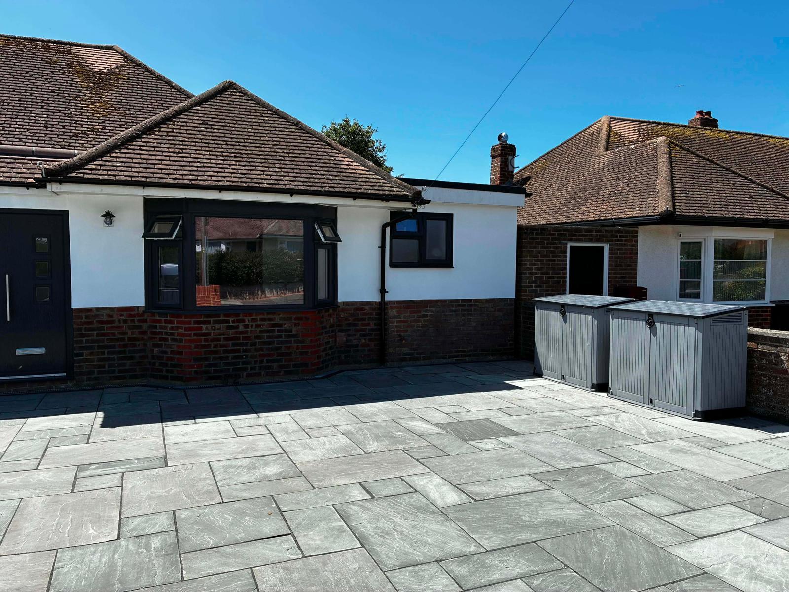 Large grey sandstone courtyard patio outside white rendered bungalow by A Baker Construction West Sussex