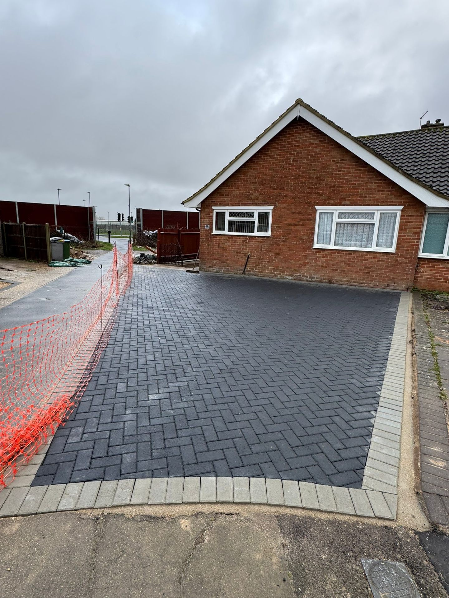 Charcoal herringbone block paved driveway with kerb edging at brick bungalow by A Baker Construction West Sussex